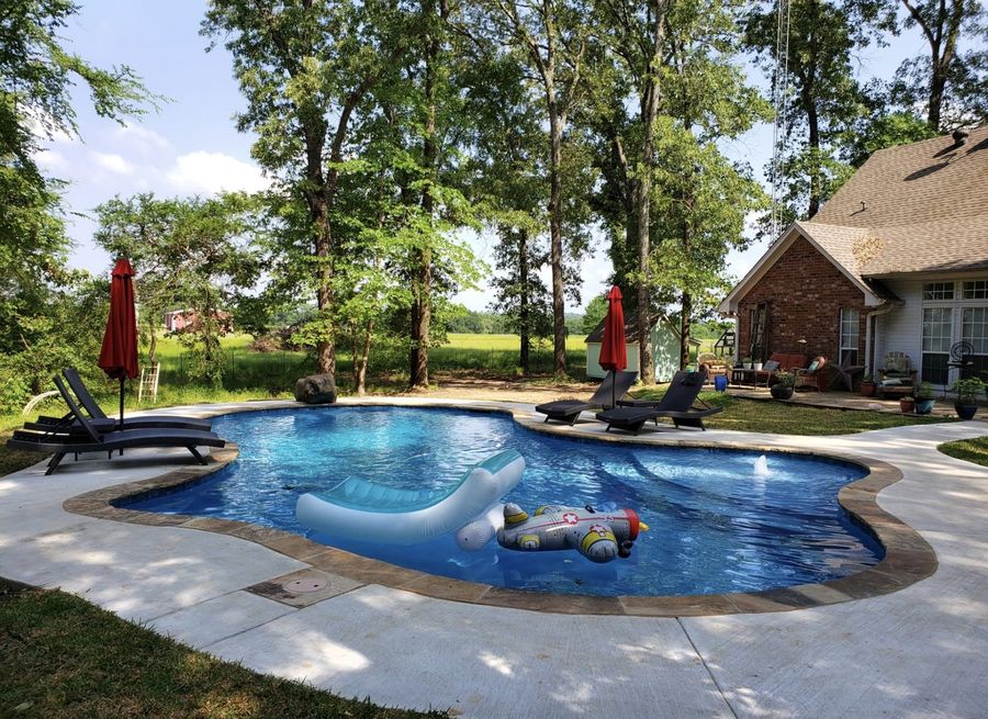 Freeform family pool with pool floats on a sunny day, East Texas pool builder