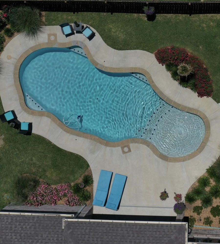 Aerial view of a teal freeform pool design by a Tyler, TX pool builder