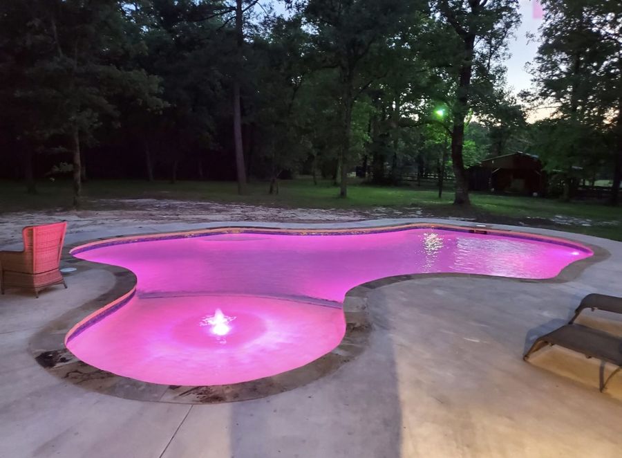 Freeform pool glowing pink from color-changing LED lighting
