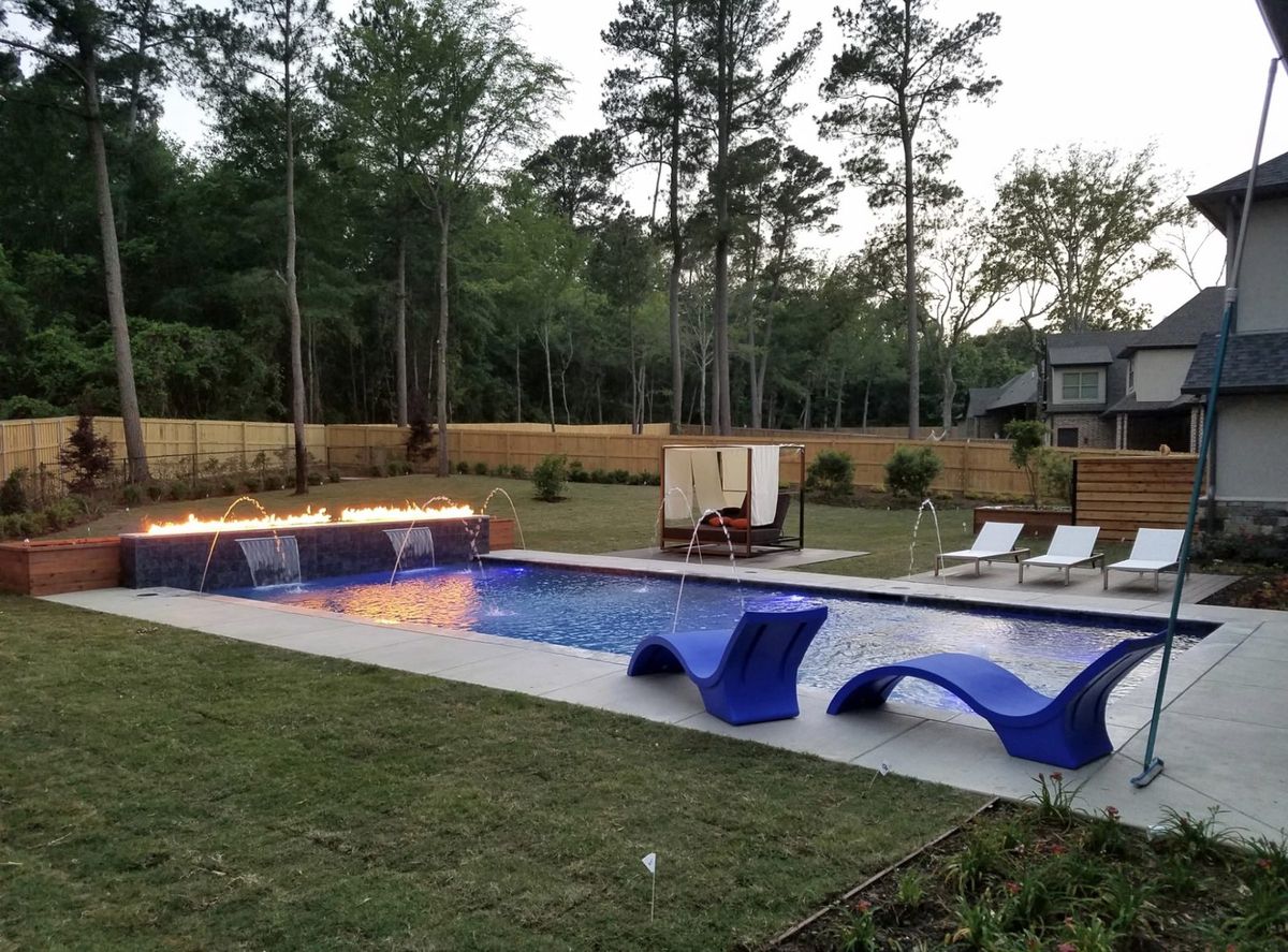 Pool with fire feature wall and water sheers at dusk, East Texas pool builder
