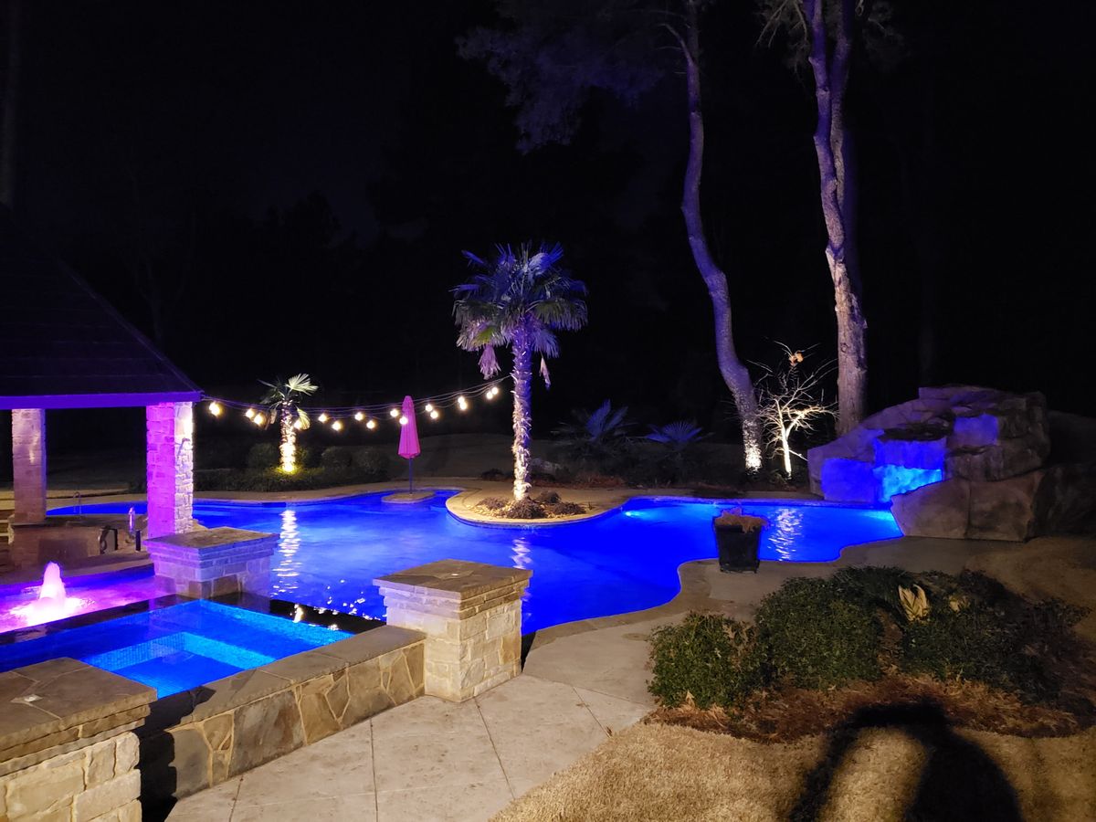 Freeform pool with LED-lit grotto waterfall and spa, custom pool builder East Texas